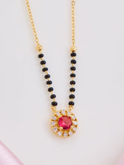 Necklace with black beads and a red gemstone pendant on a light pink background