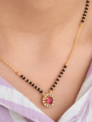 Gold necklace with a red gemstone pendant on a person wearing a light purple saree.
