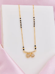 Gold necklace with black beads on a white box with pink satin border