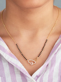Gold necklace with a heart pendant worn by a person in a striped shirt.