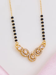 Gold necklace with black beads on a light pink background