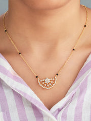 Gold necklace with a decorative pendant worn by a person in a light purple and white striped garment.