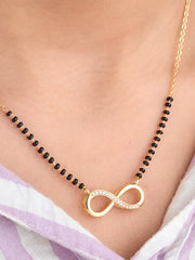 Necklace with an infinity symbol pendant on a person wearing a light purple garment.
