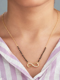 Gold necklace with an infinity symbol pendant worn by a person in a striped shirt.