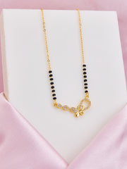 Gold necklace with black beads on a pink satin surface