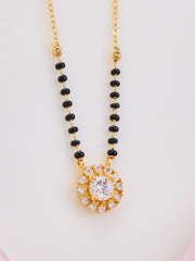 Necklace with black beads and a gold pendant on a light gray background