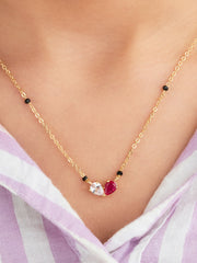 Gold necklace with gemstones worn by a person against a light background