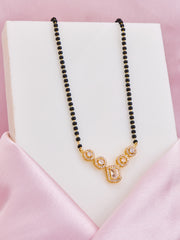 Necklace with black beads and gold clasp on a pink satin surface