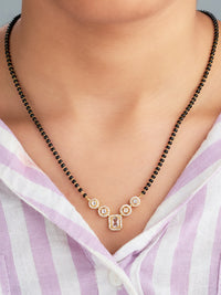 Necklace with black beads and a gold clasp worn by a person in a striped shirt.