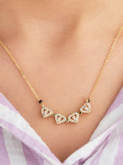 Gold necklace with heart-shaped pendants on a person wearing a light purple top.