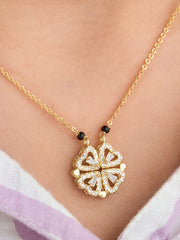 Gold necklace with a floral pendant on a person wearing a white and purple garment.