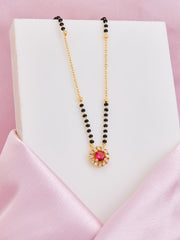 Necklace with black beads and a colorful pendant on a pink satin surface