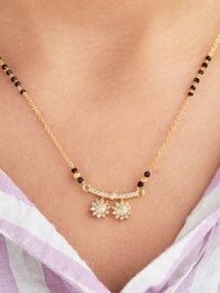 Gold necklace and earrings on a person wearing a light purple top.