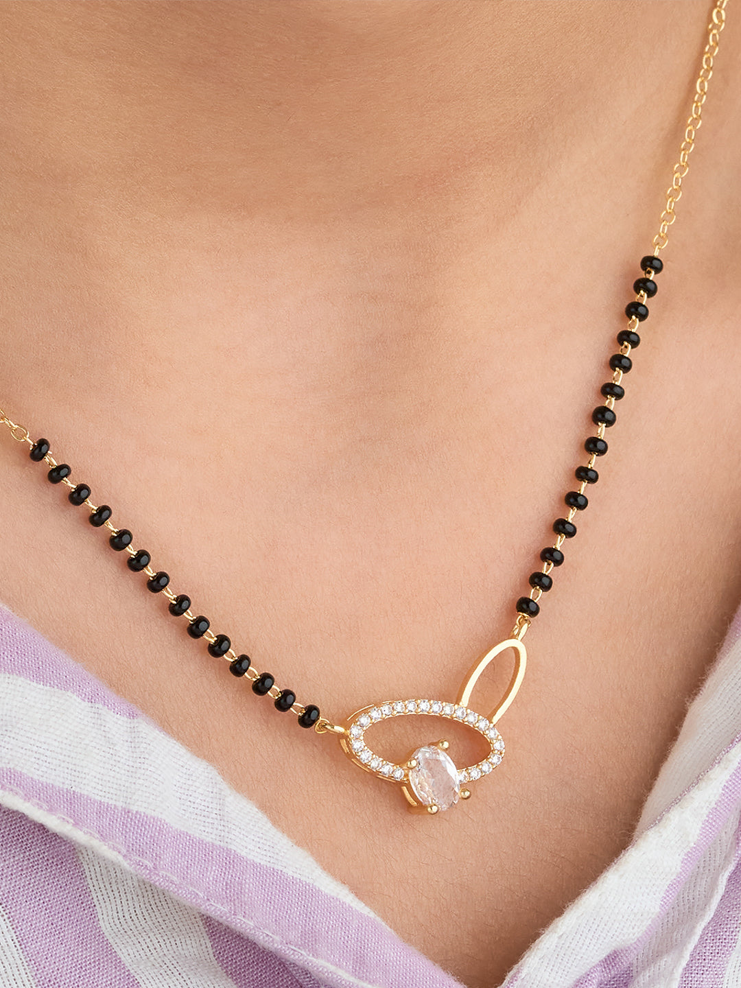 Necklace with black beads and a gold clasp worn by a person