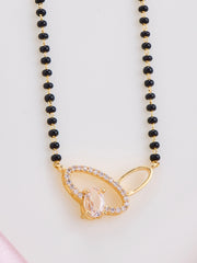 Necklace with black beads and a gold pendant on a light pink background