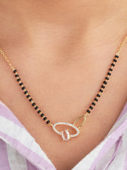 Necklace with black beads and a gold clasp on a person wearing a light purple top.