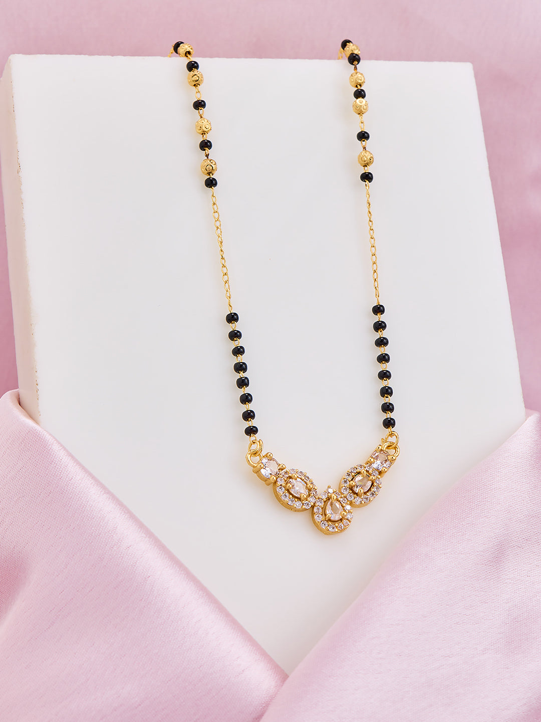 Necklace with black and gold beads on a pink satin surface