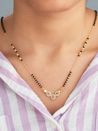 Gold necklace with black beads on a person wearing a purple and white striped shirt.