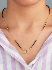 Gold necklace with black beads and a pendant on a person wearing a striped shirt.
