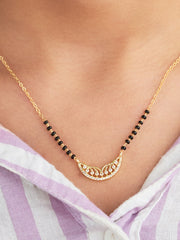 Gold necklace with black beads on a person wearing a striped garment