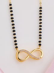 Necklace with black beads and a gold infinity symbol pendant on a light pink background