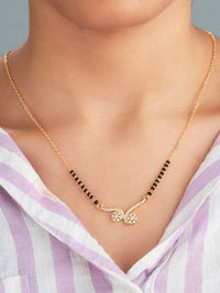 Gold necklace with black beads worn by a person in a light purple and white striped shirt.