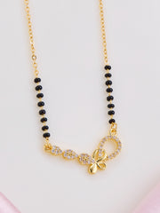Necklace with gold chain, black beads, and butterfly pendant on a light pink background
