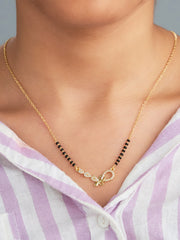 Gold necklace with black beads worn by a person in a striped shirt