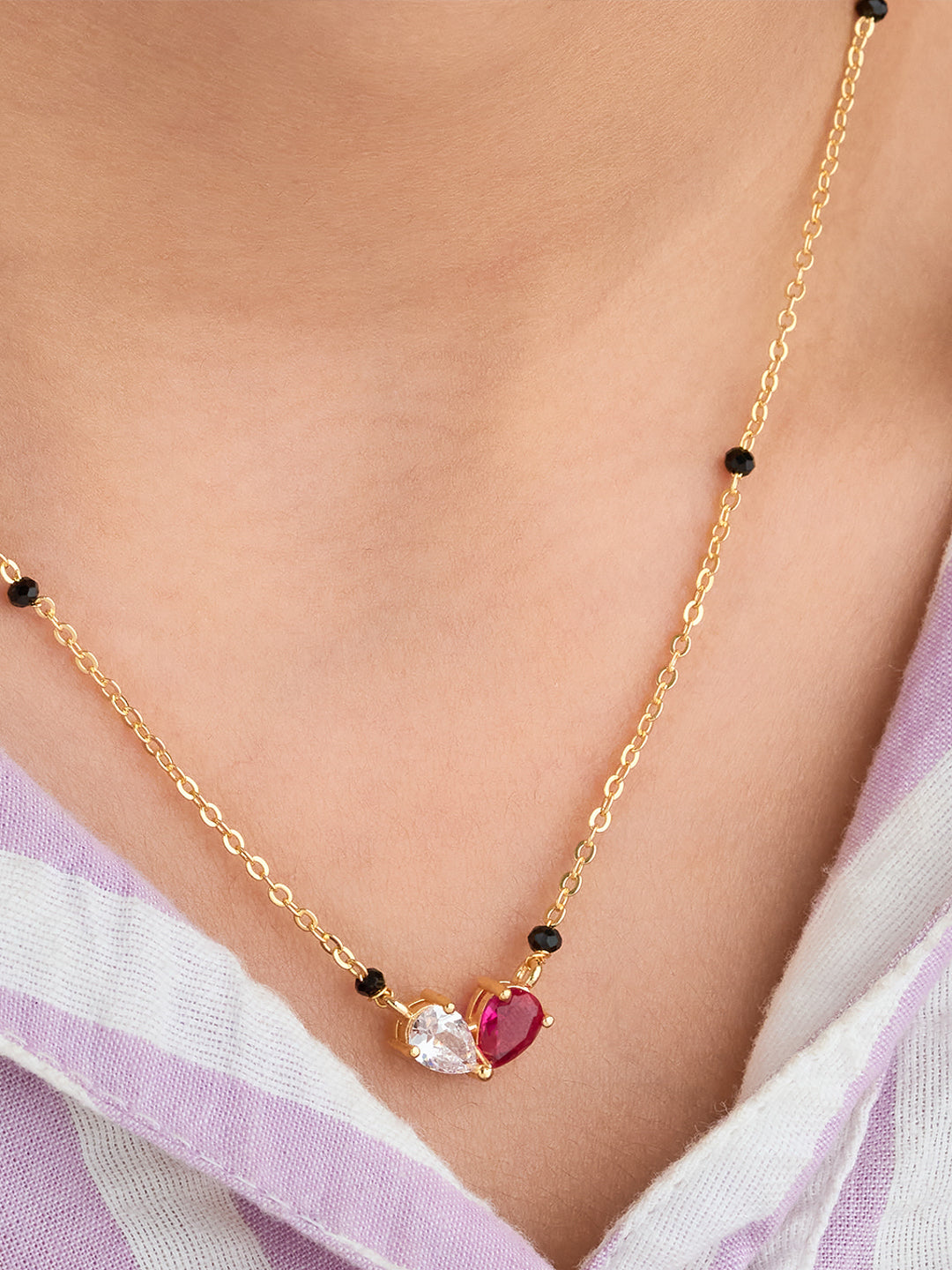 Gold necklace with heart-shaped gemstones worn by a person