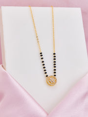 Necklace with black beads and gold clasp on a pink satin surface
