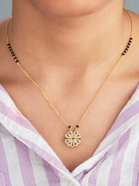 Gold necklace with a decorative pendant on a person wearing a striped shirt.