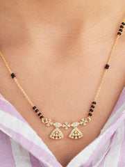 Gold necklace with black beads on a person wearing a light purple top.